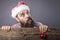 Portrait of a funny bearded man with santa cap holding a red round decoration ball