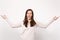 Portrait of funny blinking young woman in light clothes hold hands in yoga gesture showing tongue isolated on white