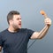 Portrait of funny chubby man shouting on phone against gray background