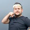 Portrait of funny chubby man wearing flower wreath on head and behaving feminine against gray background