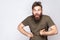 Portrait of funny crazy bearded man with tongue out and dark green t shirt against light gray background.