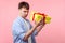 Portrait of funny dissatisfied brown-haired man holding unpacked gift box. indoor, isolated on pink