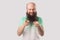 Portrait of funny excited middle aged bald man with long beard, green t-shirt standing, pointing and looking at camera with toothy