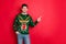 Portrait of funny funky brown hair man in deer reindeer theme sweater point index finger at copy space recommend ads