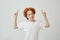 Portrait of funny ginger child with freckles pointing upside on white wall with relaxed expression Copy space for your