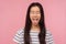 Portrait of funny girl with long hair in striped t-shirt showing tongue and keeping eyes closed with naughty childish grimace