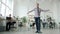 Portrait of funny hipster man dancing at work with serious people sitting at desks in background