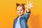 Portrait of a funny little girl on a yellow background. Preschool child shows the palm, give five