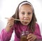 Portrait of funny lovely little girl eat honey