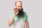 Portrait of funny middle aged bald man with long beard in light green t-shirt standing, winking and looking at camera with Ok sign