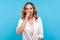 Portrait of funny positive girl sticking out tongue, picking her nose with comic naughty expression. blue background