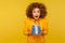 Portrait of funny surprised curly-haired young woman in urban style hoodie holding blue gift box