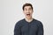 Portrait of funny weird guy shouting with popped-eyes at camera, expressing joy and happiness over gray background