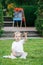 Portrait of funny white Caucasian toddler child kid boy sitting on grass ground outside in summer autumn park by drawing easel