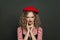 Portrait of a funny woman dressed in striped t-shirt and red french style beret grimacing on black background