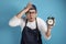 Portrait of funny young Asian male chef or waiter worried by time when looking at a clock