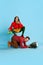 Portrait with funny, young couple, woman sitting on husband's back over blue studio background. Bossy wife