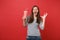 Portrait of funny young woman blinking, keeping mouth wide open, holding plastic cup of cola or soda isolated on bright