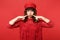 Portrait of funny young woman in lace dress, cap pointing index fingers on blowing cheeks isolated on bright red