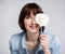 Portrait of funny young woman or teenage girl covering face with lollipop over gray