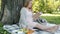 Portrait of future mother enjoying book and outdoor meal having picnic in park on sunny summer day