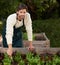 Portrait, gardener and smile with lettuce for harvest, growth or production in outdoor nursery. Man, leaning and boxes