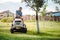 portrait of gardener smiling and mowing lawn, cutting grass in garden