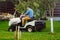 Portrait of gardener using a lawn mowing tractor for cutting grass.