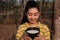 Portrait gardener young asea woman look at a full cup of raw para rubber milk of tree in plantation rubber tapping form Thailand,