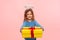 Portrait of generous kind angelic little girl with nimbus giving big birthday present to camera and smiling