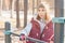 Portrait of a girl athlete in a hat with gloves and a warm vest next to a workout playground outdoors in the winter on a