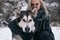 Portrait of girl with big Malamute dog on winter background.