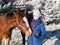 Portrait of girl in blue jacket with foals on frosty pasture