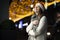 Portrait of a girl in a Christmas hat on the street, woman walks at night around the holiday city