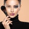 Portrait of a girl with cosmetic brush near face. Woman making makeup on the face using makeup brush. One half face of a beautiful