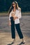 Portrait of a girl in dark sunglasses posing in city. Dressed in top with floral print, white shirt, black trousers