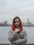 Portrait of a girl in a down jacket and a red scarf on the background of the Neva River