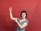 Portrait of    girl in   dress showing hands up on   red background