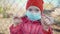 Portrait of girl in garden in medical mask with displeased sad expression on his face behind metal mesh on self