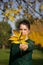 Portrait of a girl in a green tracksuit. Holds yellowed leaves in his hands. Itself is out of focus