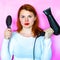 Portrait of a girl with hairdryer and hairbrush on pink background