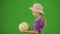 Portrait of girl in hat and rubber boots on chroma key green screen. Little cute girl gardener holding big cabbage in