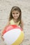 Portrait of girl holding beachball on beach smiling