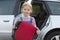 Portrait Of Girl Holding Booster Seat Standing Next To Car