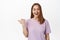 Portrait of girl laughs natural and smiling, pointing finger left at event, store promo offer, showing discount banner