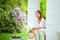 Portrait of a girl in a lilac blooming garden in spring in a white gazebo looking at the camera