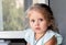 Portrait girl little cute European 3 years old with huge eyes sitting by the window