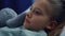 Portrait girl lying in bed with plush toy on hospital checkup in pediatric unit.