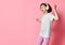 Portrait of girl of music listens in white headphones, enjoying the pleasure of listening to music against a pink background