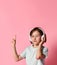 Portrait of girl of music listens in white headphones, enjoying the pleasure of listening to music against a pink background